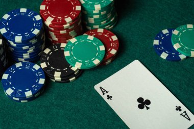 Birkaç deste poker fişi yeşil bir masanın üzerinde duruyor ve yanında da Sinek Ası kartı var. Akşamları kumarhane atmosferinde oyuna odaklanıyorlar..