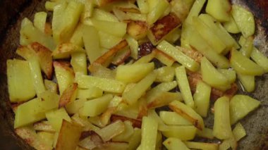 Kızartma tavasında dilimlenmiş patatesler pişirdikçe renkleri ve dokuları yavaş yavaş değişiyor, kahverengi ve çıtır çıtır kenarları gösteriyor, pişirme sürecine ve yağ miktarına yakından bakıyor