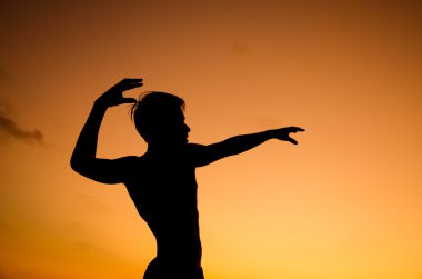 bir şey üzerinde gökyüzü günbatımı üzerinde işaret eden bir adamın siluet resmi