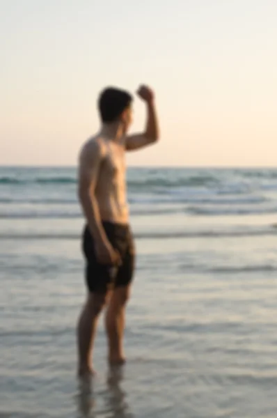 Homme debout à la plage au coucher du soleil — Photo