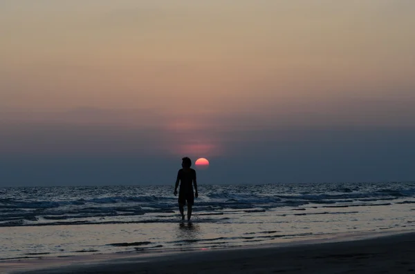 Silueta muže, chůze na západ slunce na pláži — Stock fotografie