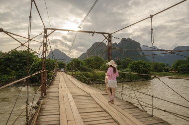 Kadın turist bir ahşap köprü üzerinde yürüme