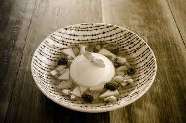 Pannacotta beyaz tabak içinde taze meyve ile.