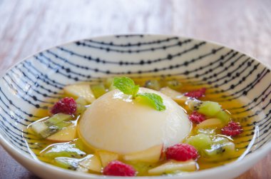 Pannacotta beyaz tabak içinde taze meyve ile.