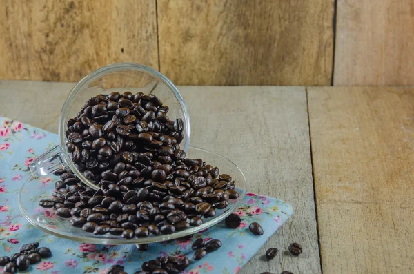 Kaffeebohnen mit Tasse auf Holztisch — Stockfoto