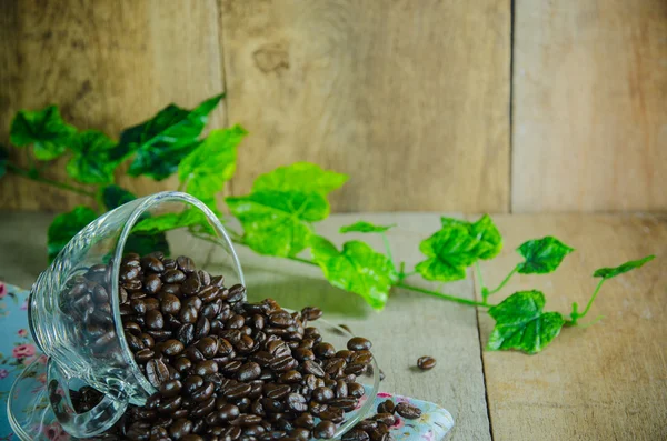 Kaffeebohnen mit Tasse auf Holztisch — Stockfoto