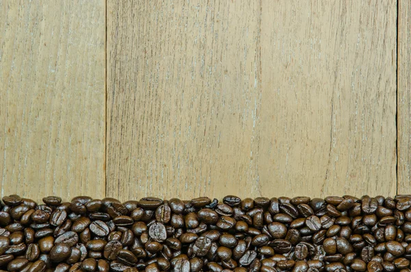 Granos de café tostados sobre fondo de madera — Foto de Stock