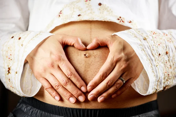 怀孕的女人用她的双手创造心的形状 — 图库照片