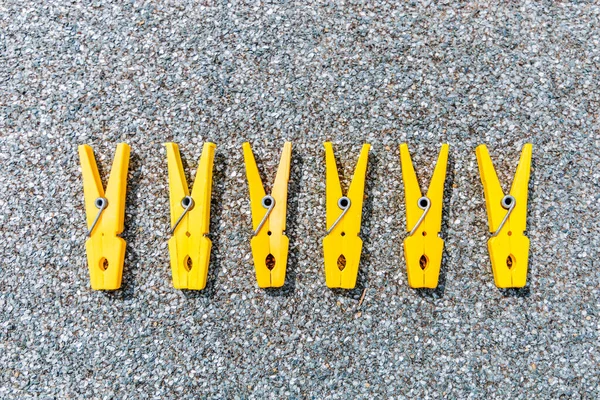 A few yellow clothes clips in a raw on grey background