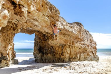 Genç dağcı Portekiz, Algarve 'de güvenli bir şekilde sarı bir uçuruma tırmanıyor.