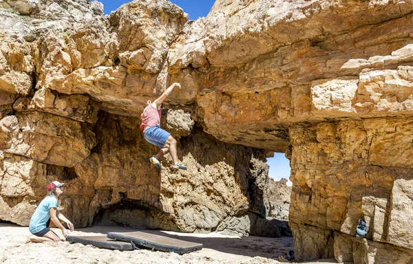 A climber falling off the rock on safety mats on the beach, Algarve, Portugal, Europe