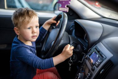 Küçük çocuk direksiyonda eğleniyor.
