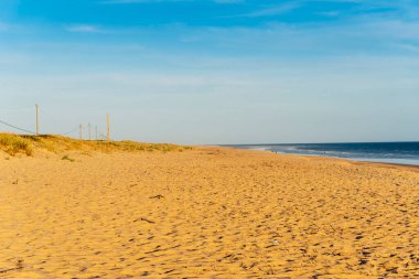 Günbatımında kum tepeleri ve yürüyüş yolları olan geniş kumlu Faro plajı, Faro, Algarve, Portekiz
