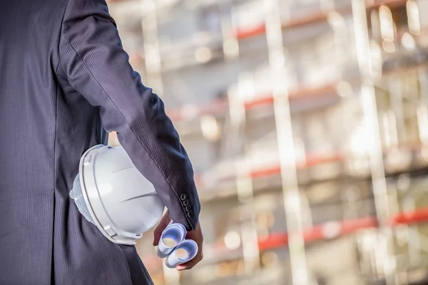 Witte helm en blauwdrukken op de bouwplaats — Stockfoto