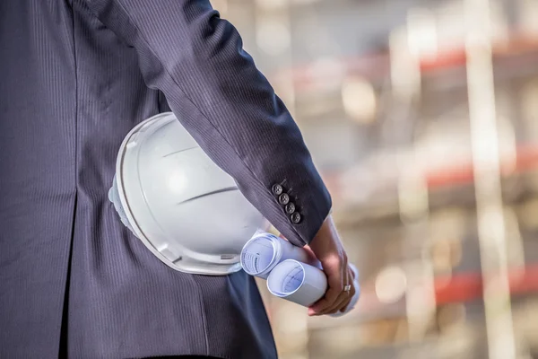 Witte helm en blauwdrukken op de bouwplaats — Stockfoto