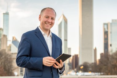 Ofis binaları önünde tablet ile işadamı
