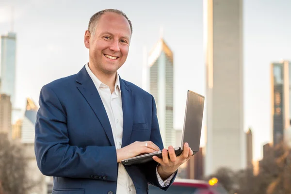 Empresário com laptop na frente de edifícios de escritórios — Fotografia de Stock