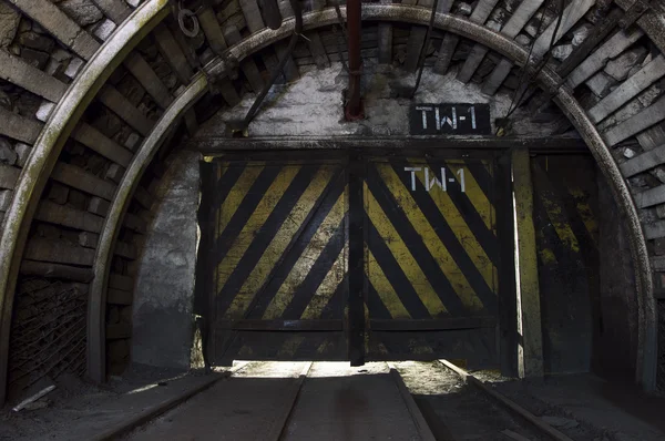 Gate in underground illuminated tunnel — Stock Photo, Image