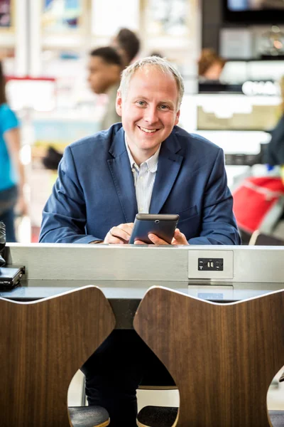 Empresário usando seu tablet no aeroporto — Fotografia de Stock