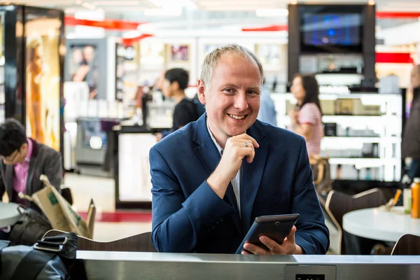 Empresário usando seu tablet no aeroporto — Fotografia de Stock