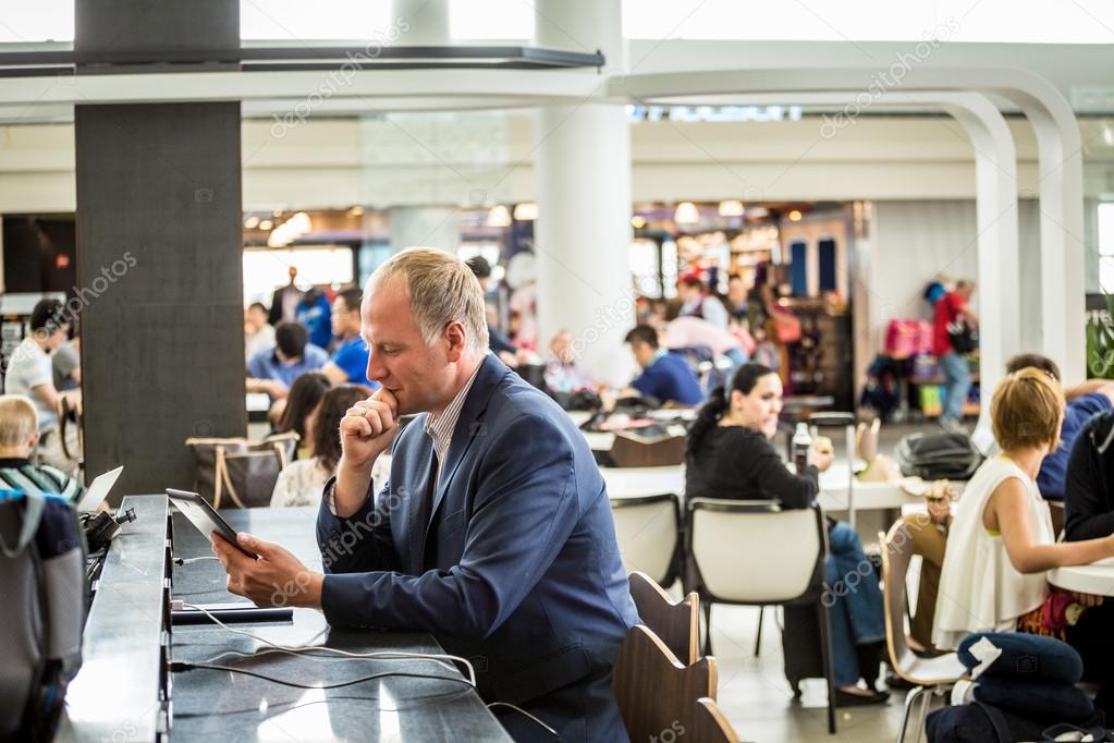 Businessman using his tablet at the airport