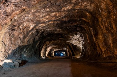 Loule, Algarve 'deki yeraltı kaya tuzu madeni tüneli, engebeli maden duvarları, endüstriyel aydınlatma ve derin toprak madencilik altyapısını gösteren kablolar..