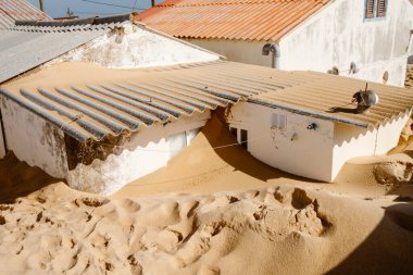 Portekiz 'in Faro Sahili' ndeki küçük geleneksel balıkçıların evleri, şiddetli kış fırtınaları sonrasında neredeyse tamamen kuma gömüldü. Kapılar, pencereler ve girişler, kıyı aşınmasının ve güçlü rüzgarların çarpıcı etkisini vurgulayarak kapatıldı. Bu sce