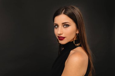 Çekici Avrupalı kız kameraya bakıyor. Siyah kıyafetli güzel bir kadın model fotoşopun tadını çıkarıyor. Yüksek kalite fotoğraf