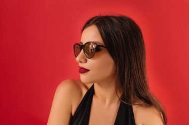 İç mekan portresi, kırmızı arka planda güneş gözlüğü takan beyaz saçlı çekici bir kadın profili. Yüksek kalite fotoğraf