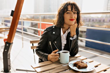 Kahve molasında terasta oturan kısa kıvırcık saçlı, kızıl dudaklı, rüya gibi bir kız. Yüksek kalite fotoğraf