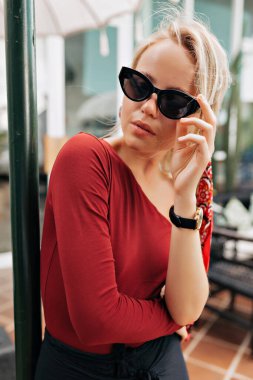 Güneş gözlüklü güzel bir bayanın dışarıda gözlüklerine dokunurken çekilmiş portresi. Yüksek kalite fotoğraf