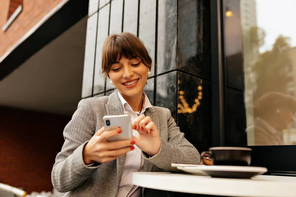 Adorável Jovem Morena Com Jaqueta Cinza Camisa Branca Usando Smartphone Imagens De Bancos De Imagens