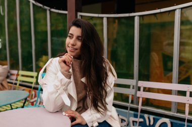 Harika çekici genç bayan şık açık hava kafesinde arkadaşlarını bekliyor. Açık hava restoranında dinlenen Fransız klasik kıyafetiyle gülümseyen esmer bir kadın. Yüksek kalite fotoğraf