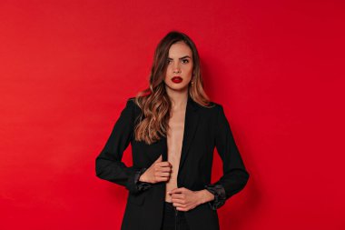 Kırmızı arka planda kırmızı dudaklarla poz veren ve Sevgililer Günü 'nü kutlayan siyahlı muhteşem stil sahibi kadının stüdyo portresi. Yüksek kalite fotoğraf