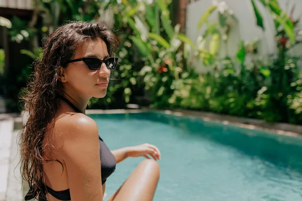 Portrét mladé atraktivní ženy s dlouhými mokrými vlasy v plavkách odpočívající v blízkosti bazénu v slunečném teplém dni — Stock fotografie