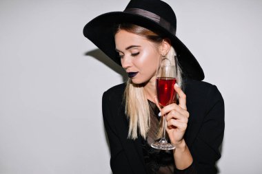 Tatil günlerinde elinde bir bardak şarap şapkasıyla kadınların bayramını kutlarken poz veren sevimli sarışının yakın portresi. Yüksek kalite fotoğraf
