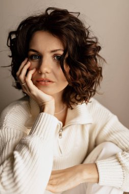 Sağlıklı ciltli, beyaz bluz giyen kıvırcık saçlı güzel bir kadının portresi. Yüksek kalite fotoğraf