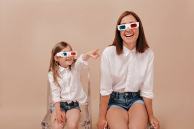 Gülümseyen, kısa saçlı, beyaz gömlekli mutlu bir kadın, küçük kızıyla birlikte mutlu bir şekilde film izliyor. Yüksek kalite fotoğraf