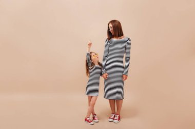 Bej arka planda poz veren küçük sevimli kızıyla birlikte genç bir kadın. Yüksek kalite fotoğraf