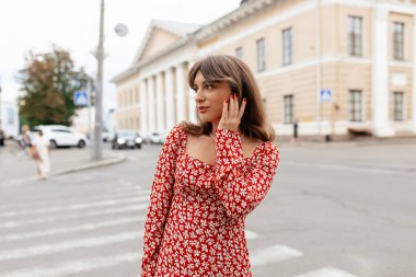 Neşeli, zarif, esmer kadın. Keyfi yerinde, dışarıda yürüyor. Kırmızı elbiseli kadın hafta sonunu şehirde geçiriyor.