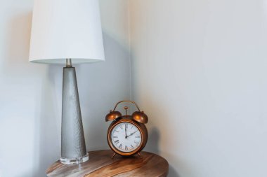 Alarm saati ve okuma lambası komodinin üzerinde. Geçmiş metni kopyala