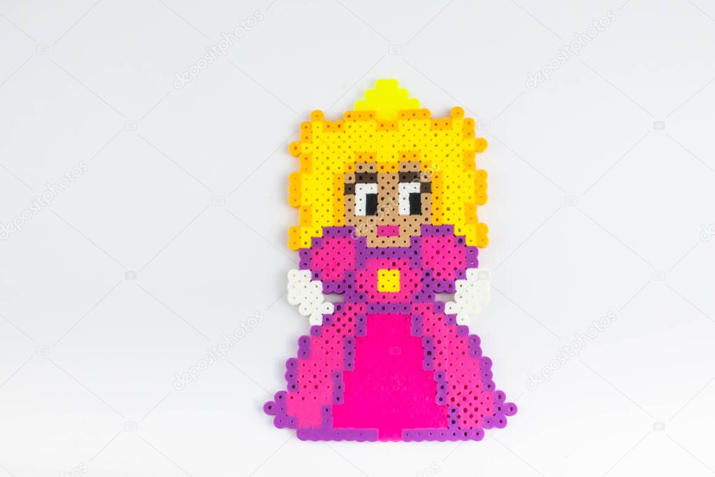 Perler bead princess in a pink dress. Perler bead doll in a pink dress.White isolated background.