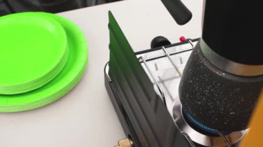 Seyahatte taşınabilir gaz ocağı alevi, yakın çekimde kahve demliği kağıt tabakları olan bir masaya koy.