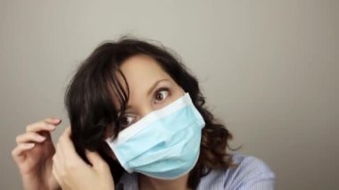 Tıbbi maske takan genç bir bayana yaklaş. Güzel beyaz iş kadını kameraya bakıyor ve kıvırcık saçlarını düzeltiyor. Sağlık, meslek, iş konsepti.