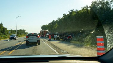 Mont-Tremblant QC Canada - 22.09.2024: Görüntü, polis arabaları ve ambulanslar da dahil olmak üzere yolun kenarına park edilmiş birden fazla acil durum aracının bulunduğu kalabalık bir şehir merkezini gösteriyor. Seyirciler yakınlarda toplandıkça parlayan ışıklar bölgeyi aydınlatıyor..