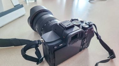 Masaya yerleştirilmiş büyük mercekli profesyonel kamera, fotoğraf meraklıları ve profesyoneller için karmaşık tasarımı ve gelişmiş özelliklerini vurguluyor.