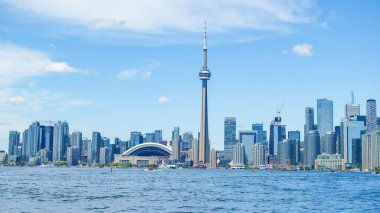 Toronto ON, Kanada - 3 Temmuz 2022: CN Tower ve Rogers Centre 'ın canlı mavi gökyüzü ve su yansımalarının yer aldığı Toronto silueti çarpıcı bir kentsel manzara yaratıyor