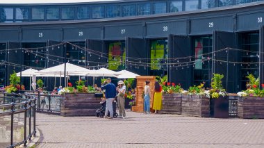 Toronto ON, Kanada - 4 Temmuz 2022: İnsanlar açık hava pazarında toplanıp renkli çiçekler ve sicim ışıklarıyla çevrili yiyeceklerin tadını çıkararak canlı bir atmosfer yaratıyor