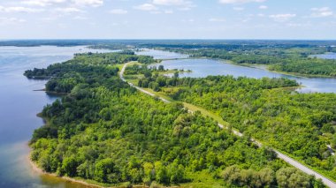 Aerial perspective reveals a vibrant green landscape with winding river and serene lakes, highlighting the beauty of nature and peaceful environment