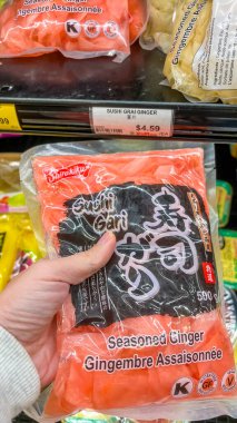 Ottawa On, Kanada - 29 Ağustos 2025: Bir el bir markette canlı bir suşi gari zencefil paketini tutuyor, renkli tasarımı ve mutfak cazibesini vurguluyor